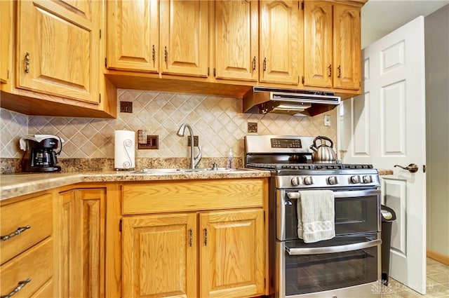 kitchen featuring tasteful backsplash, range with two ovens, light stone countertops, under cabinet range hood, and a sink