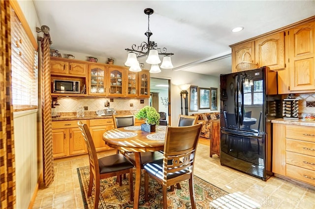 interior space featuring decorative light fixtures, stainless steel microwave, decorative backsplash, glass insert cabinets, and freestanding refrigerator