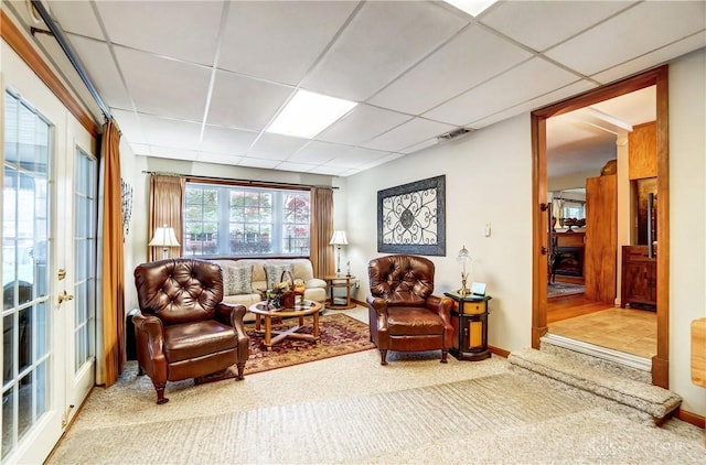 sitting room featuring carpet floors, baseboards, visible vents, and a drop ceiling