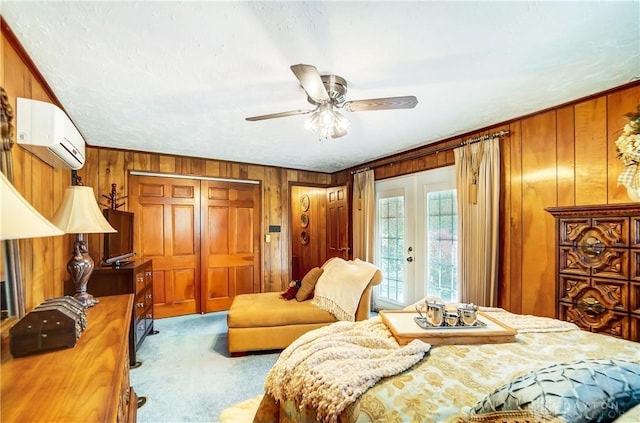 bedroom with a ceiling fan, a wall unit AC, carpet, french doors, and wood walls