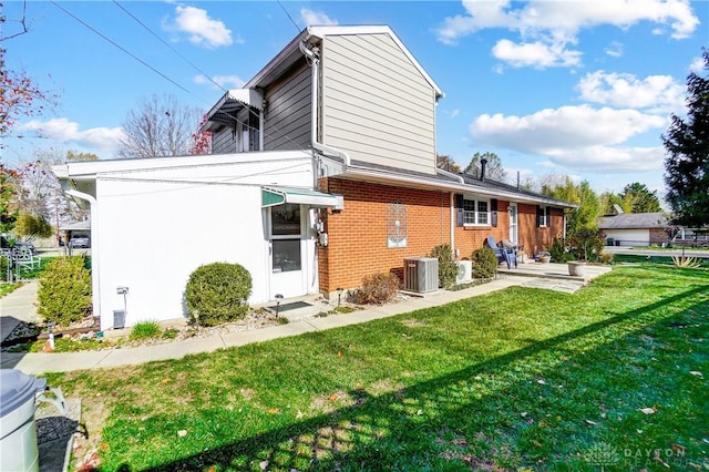 rear view of property with brick siding, a lawn, and central air condition unit