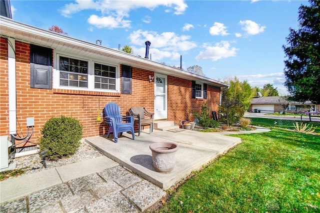 rear view of property featuring a patio area, fence, a lawn, and brick siding