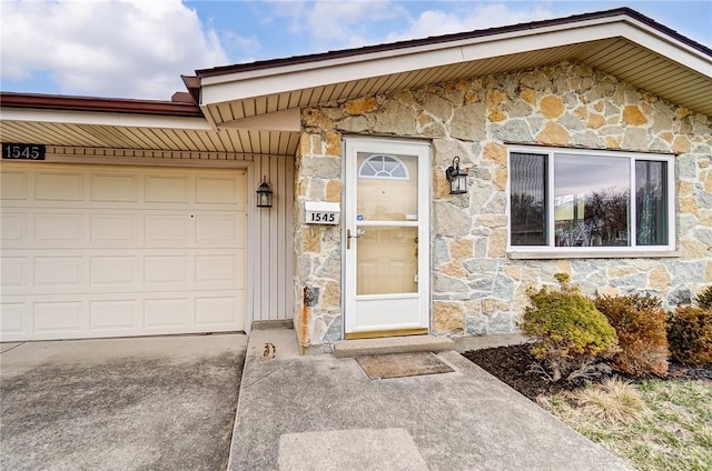 entrance to property featuring an attached garage and stone siding