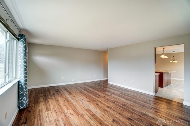 spare room with light wood-type flooring, baseboards, and a chandelier