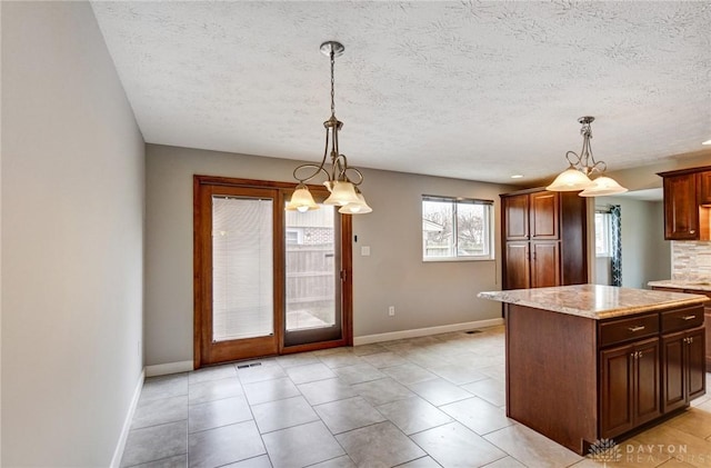 kitchen featuring light stone counters, decorative light fixtures, and baseboards