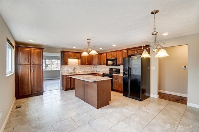 kitchen featuring visible vents, light countertops, a center island, black appliances, and tasteful backsplash