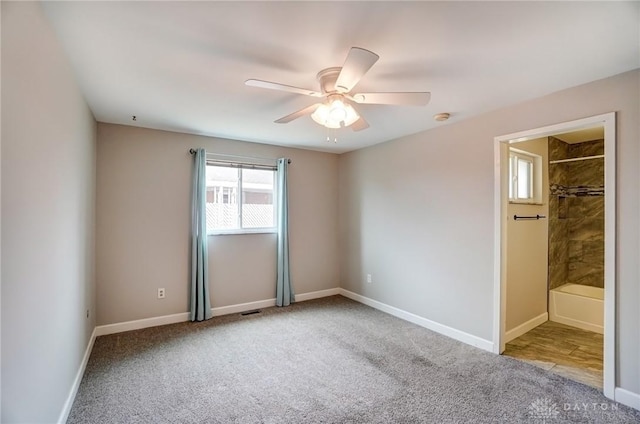 carpeted empty room featuring baseboards and a ceiling fan