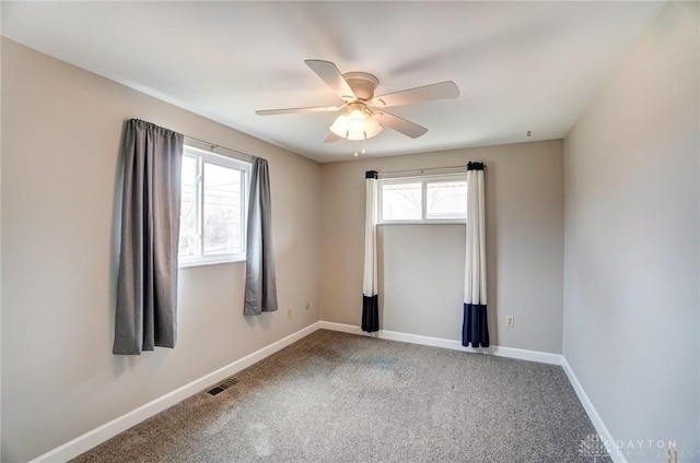 spare room with a ceiling fan, carpet flooring, visible vents, and baseboards