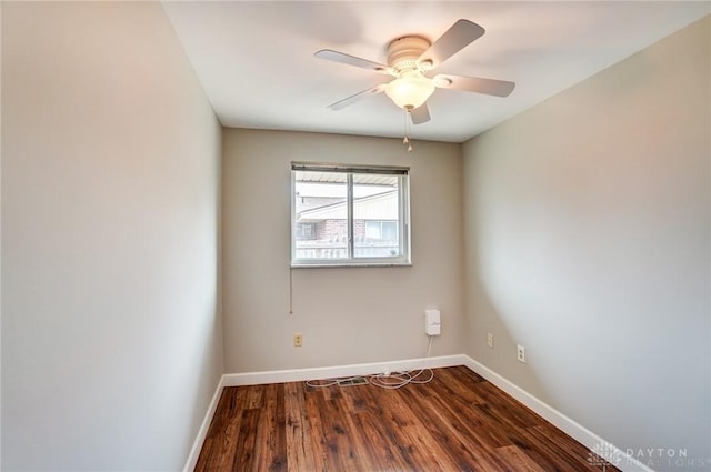 spare room featuring a ceiling fan, baseboards, and dark wood-style flooring