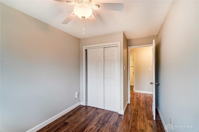 unfurnished bedroom featuring dark wood-style floors, a closet, ceiling fan, and baseboards