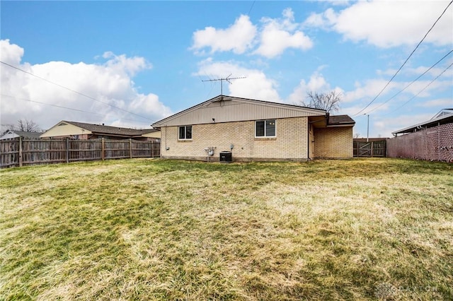 back of house with brick siding, a yard, a fenced backyard, and central air condition unit