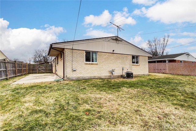 rear view of house featuring a patio, brick siding, a lawn, and a fenced backyard