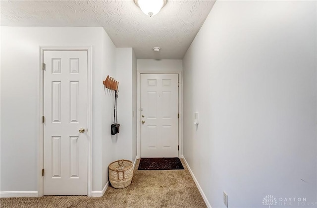 entryway with carpet, baseboards, and a textured ceiling