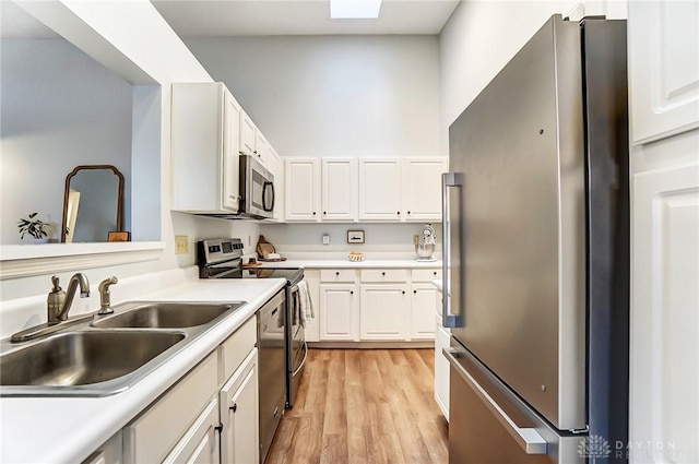 kitchen featuring stainless steel appliances, a sink, light countertops, and white cabinets