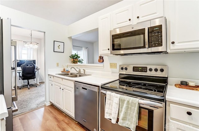 kitchen featuring stainless steel appliances, a sink, light countertops, and white cabinetry