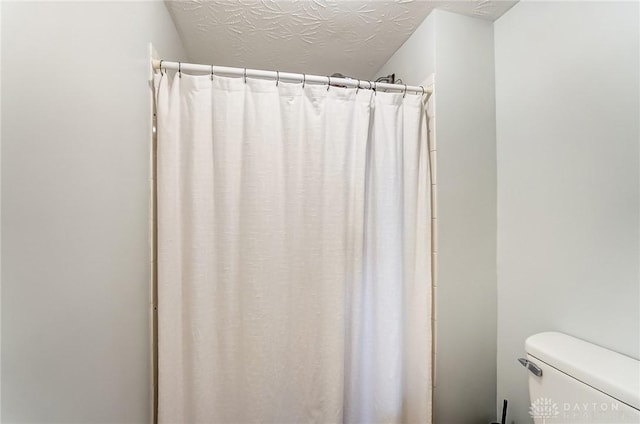 full bath featuring toilet, a shower with curtain, and a textured ceiling