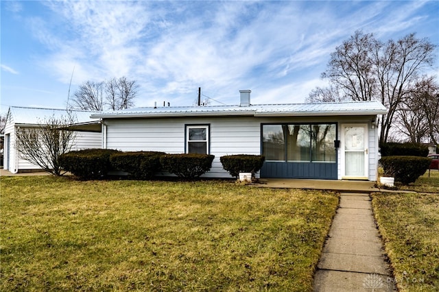 back of house featuring metal roof and a yard