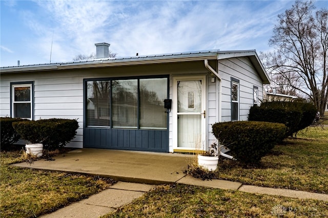 doorway to property with metal roof and a patio