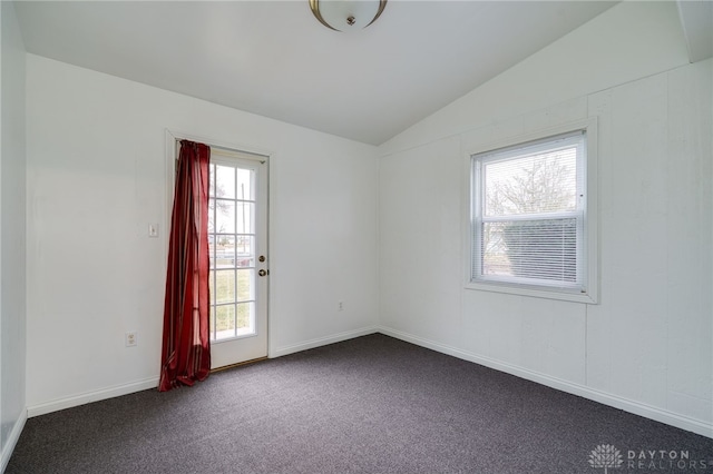 spare room with baseboards, dark carpet, and vaulted ceiling