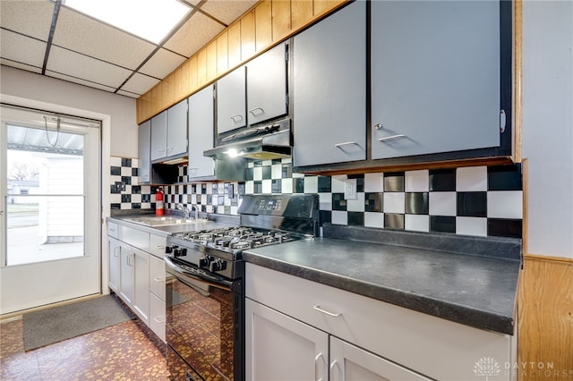 kitchen with dark countertops, a paneled ceiling, black gas stove, a sink, and under cabinet range hood