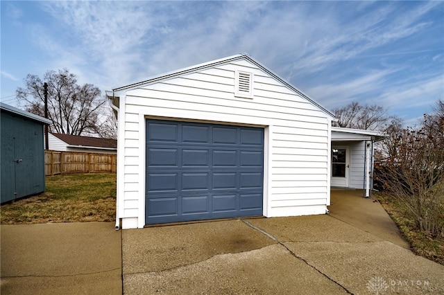 detached garage with concrete driveway and fence