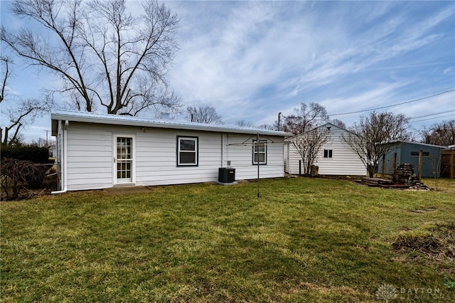 back of house featuring metal roof, a yard, an outdoor structure, and central AC unit