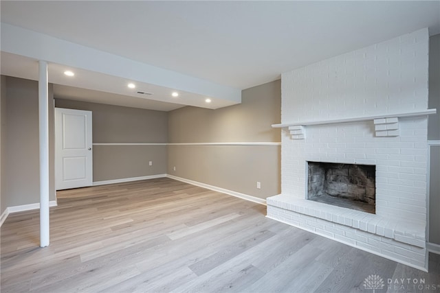 unfurnished living room with a brick fireplace, baseboards, wood finished floors, and recessed lighting