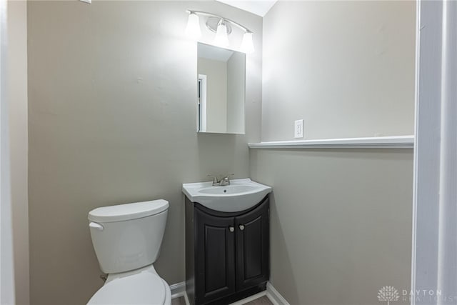 bathroom with toilet, baseboards, and vanity