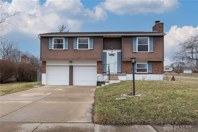 split foyer home with a garage, brick siding, concrete driveway, a chimney, and a front yard