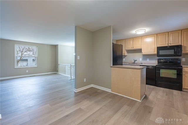 kitchen with a sink, light wood-style floors, light countertops, light brown cabinetry, and black appliances