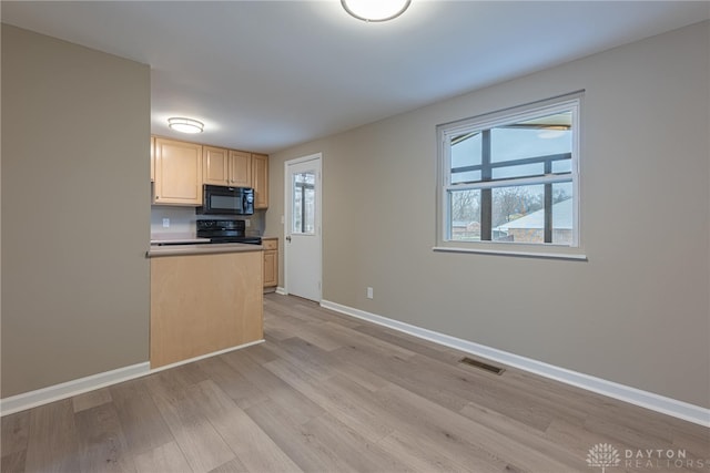 kitchen featuring light brown cabinets, visible vents, black appliances, light wood finished floors, and plenty of natural light