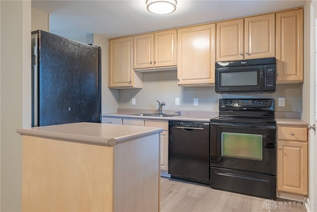 kitchen featuring light countertops, a sink, black appliances, and light brown cabinetry