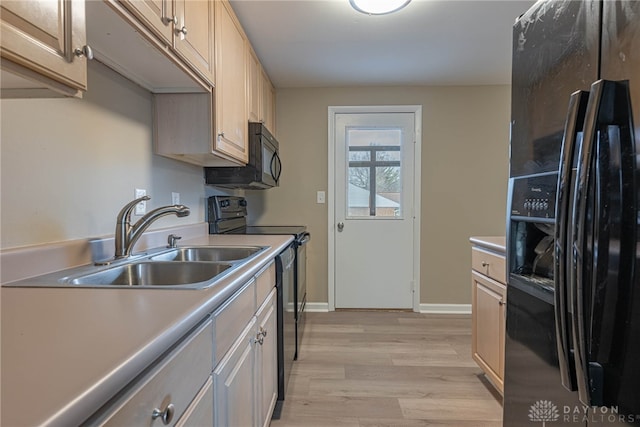 kitchen featuring baseboards, light wood-style flooring, light countertops, black appliances, and a sink