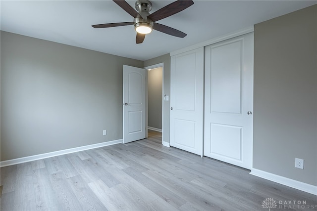 unfurnished bedroom featuring a ceiling fan, light wood-style flooring, baseboards, and a closet