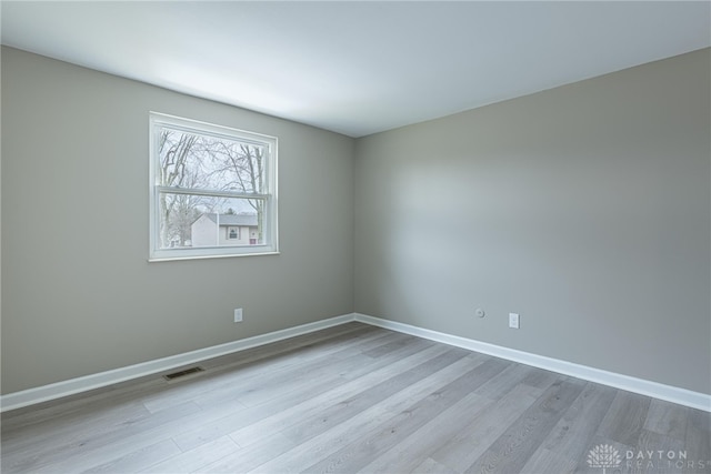 spare room with baseboards, visible vents, and wood finished floors