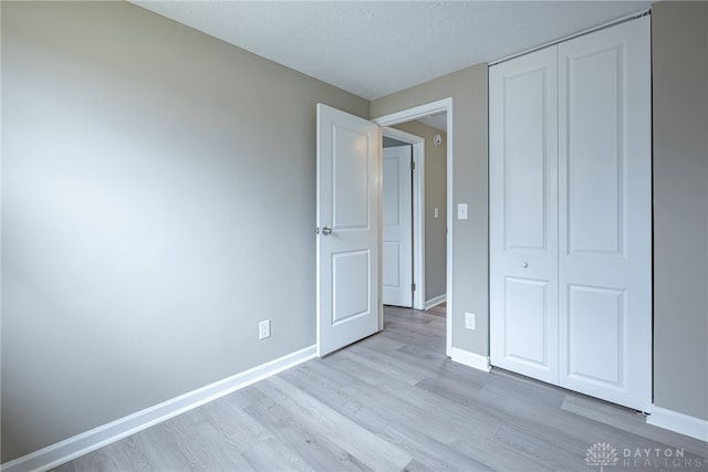 unfurnished bedroom with a closet, baseboards, and wood finished floors