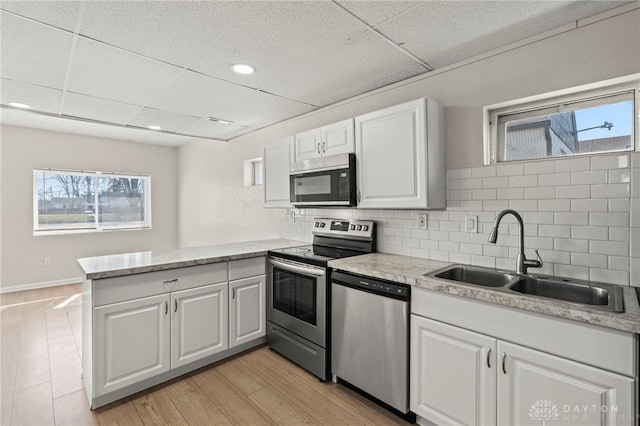 kitchen featuring stainless steel appliances, a peninsula, a sink, and light countertops