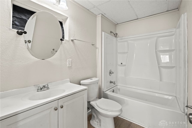 bathroom featuring a paneled ceiling, vanity, toilet, and a textured wall