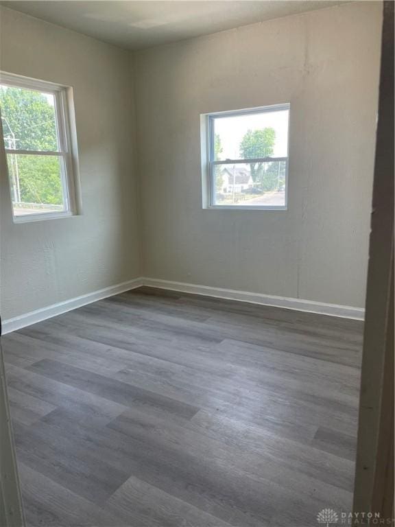 spare room with dark wood-type flooring and baseboards