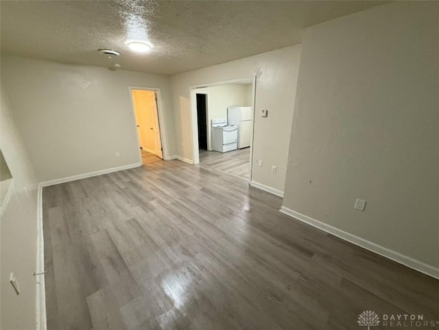 spare room with a textured ceiling, wood finished floors, and baseboards