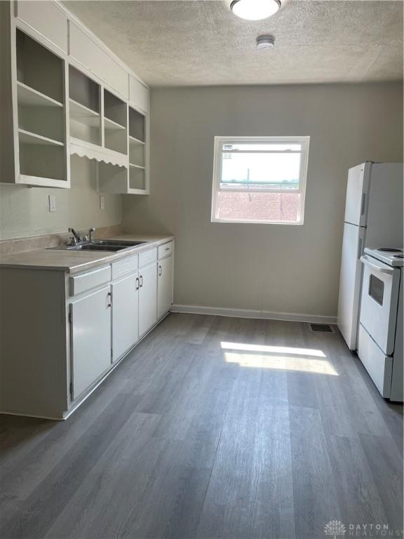 kitchen featuring baseboards, wood finished floors, a textured ceiling, white electric range, and a sink