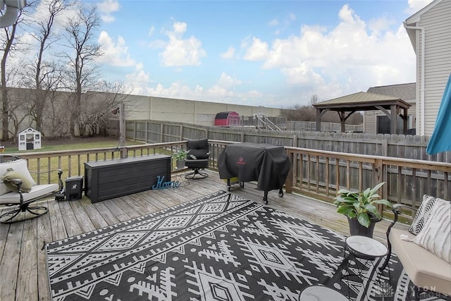 wooden terrace with a storage shed, grilling area, an outbuilding, fence, and a gazebo