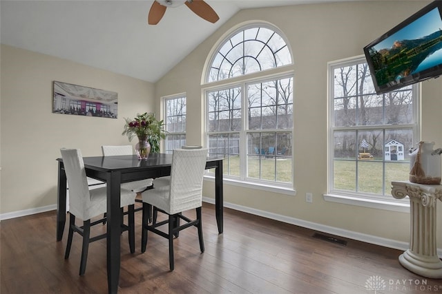 dining space with baseboards, visible vents, a ceiling fan, dark wood-style floors, and high vaulted ceiling