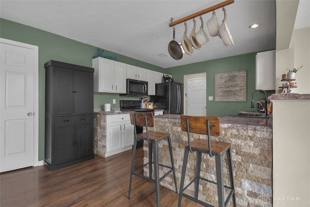 kitchen with dark wood-style floors, white cabinetry, a sink, and black appliances