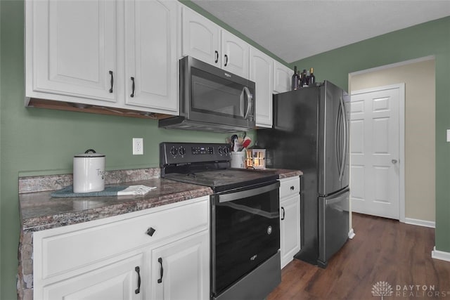 kitchen featuring electric range, dark stone counters, white cabinets, dark wood-style floors, and stainless steel microwave