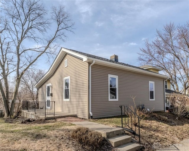 view of side of property featuring a chimney and a wooden deck