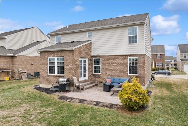 back of property with a yard, a patio, and brick siding