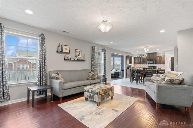 living room featuring recessed lighting, visible vents, dark wood-type flooring, a textured ceiling, and baseboards