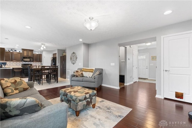 living area with baseboards, wood finished floors, and recessed lighting