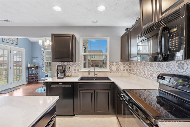 kitchen with visible vents, a sink, black appliances, and dark brown cabinets